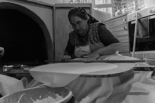 A woman expertly rolling out dough in a traditional Turkish kitchen setting.