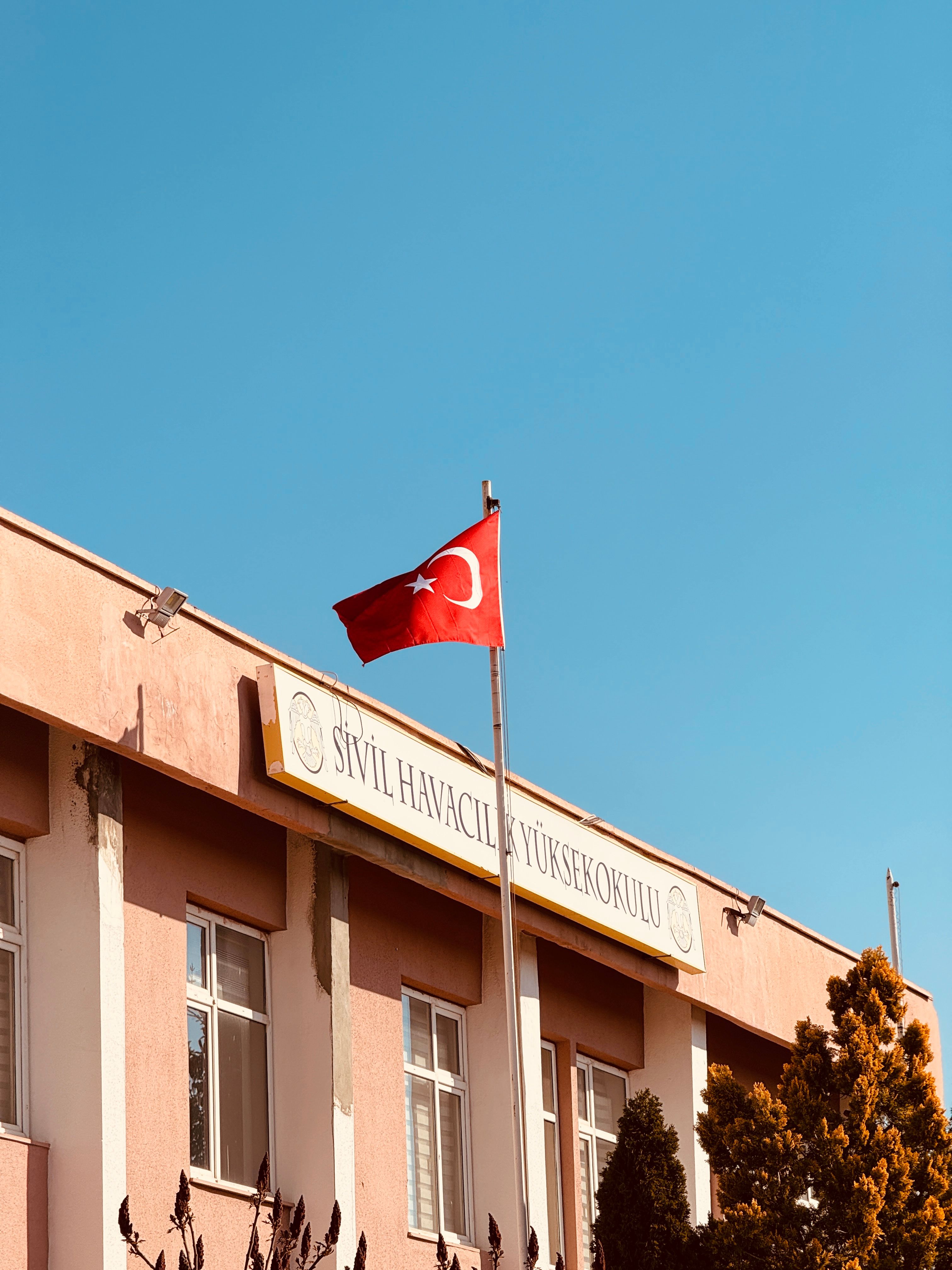 Exterior of the Sivil Havacılık Yüksekokulu in Konya, Türkiye with the Turkish flag waving.