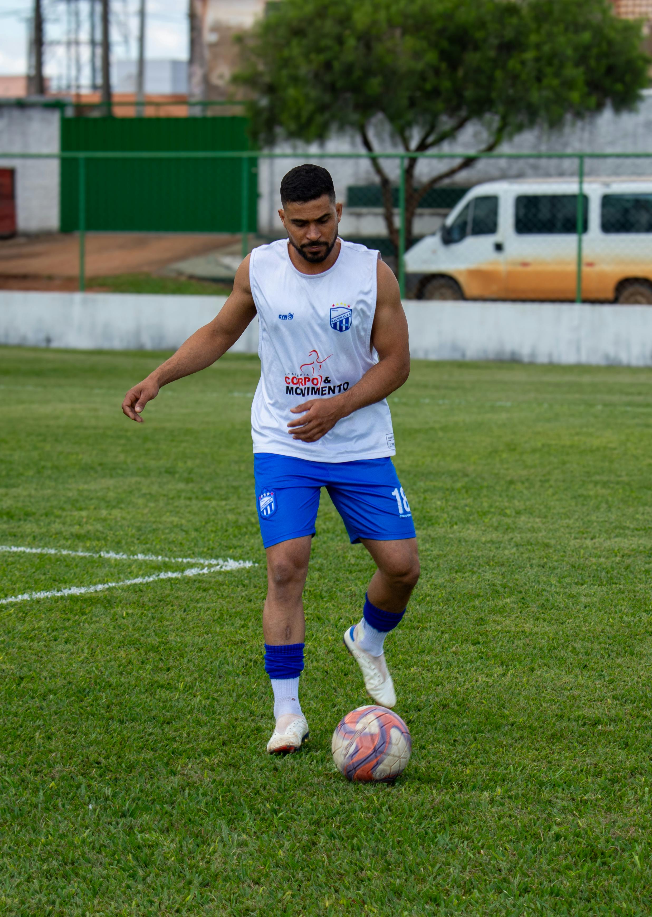 Adult male soccer player practicing on an outdoor grass field, focusing on ball control.