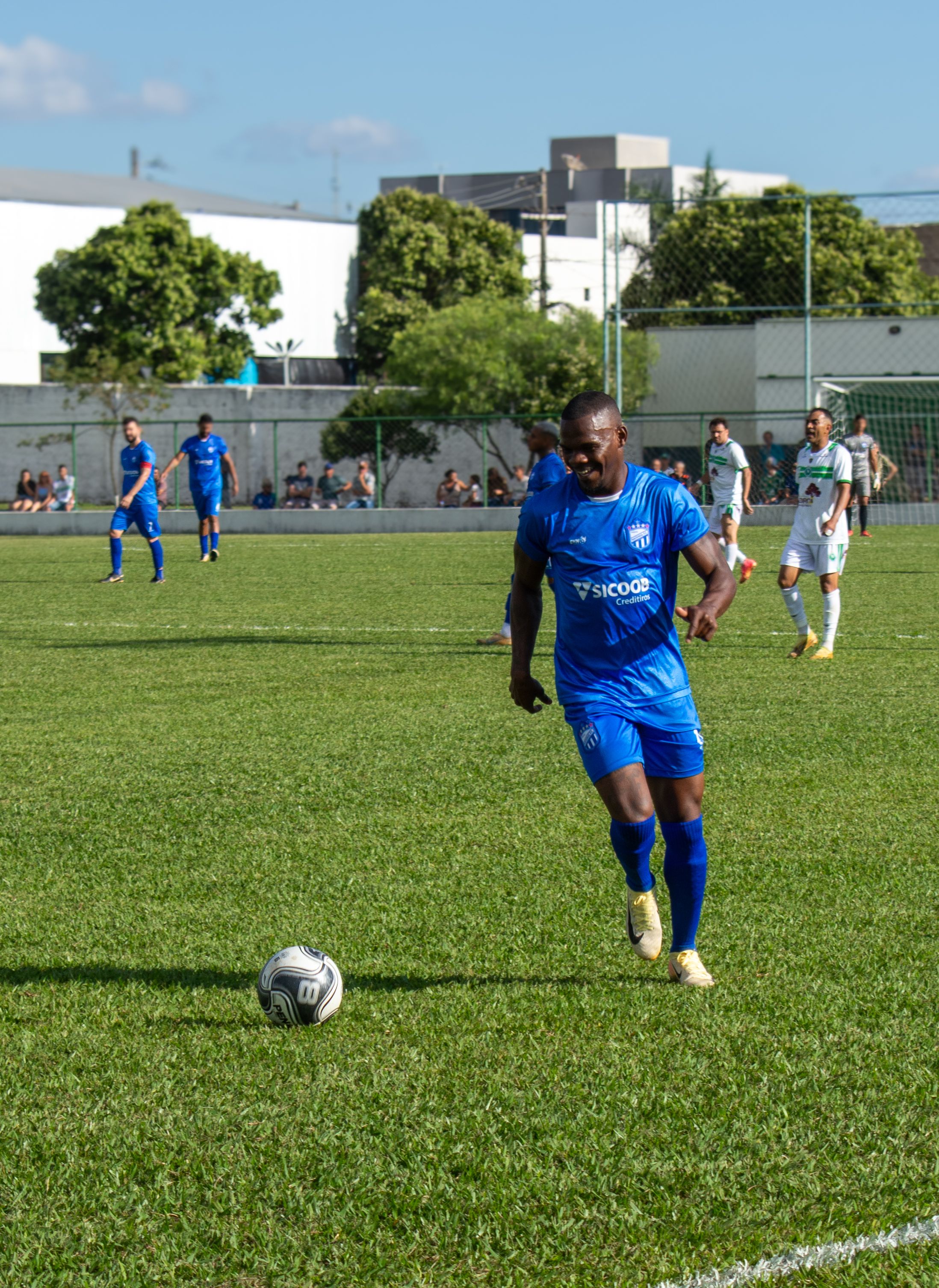 Soccer match with players in blue and white jerseys on a sunny day.