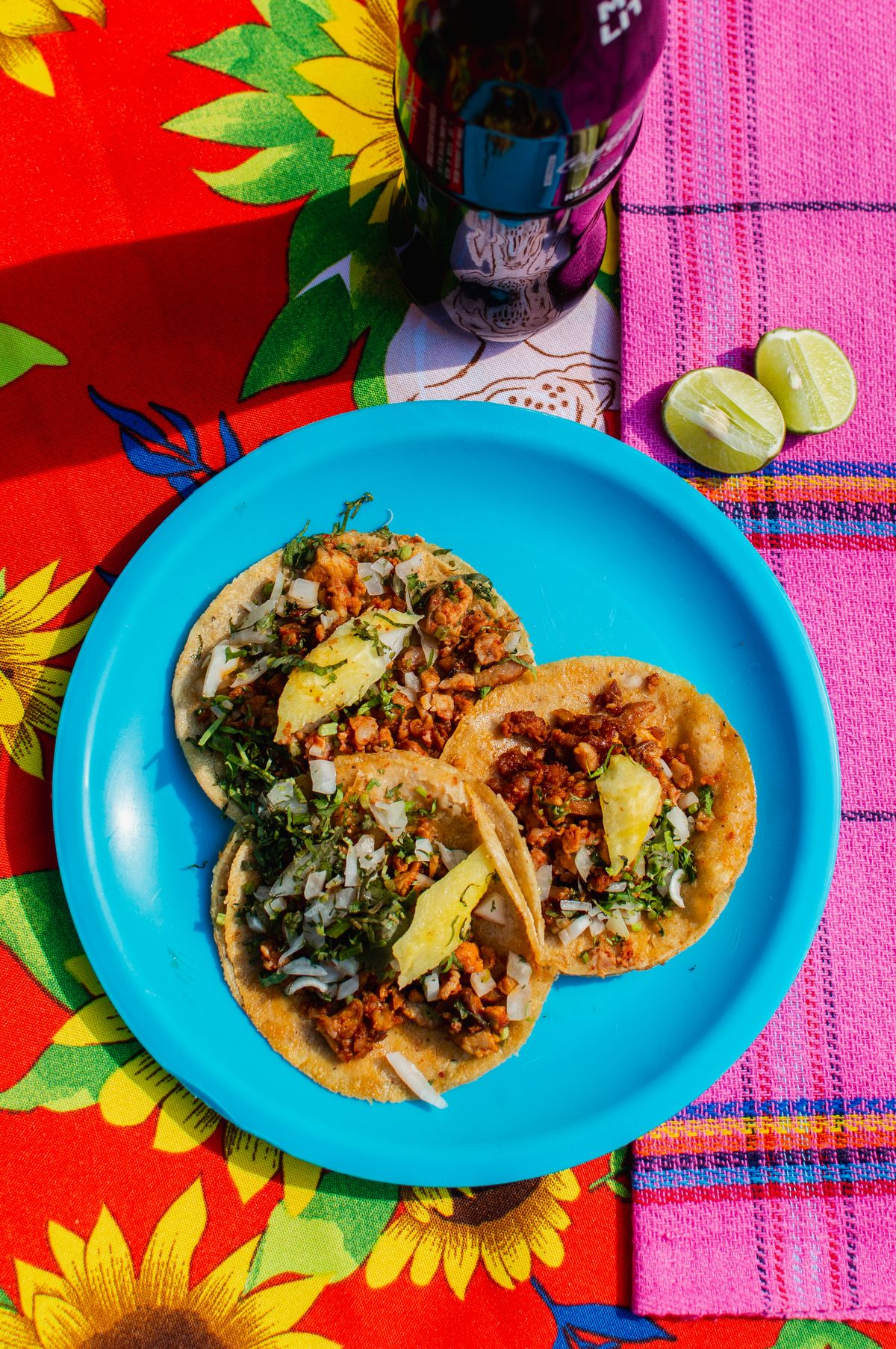 Delicious Mexican tacos al pastor served on a vibrant table setting with limes and soda.