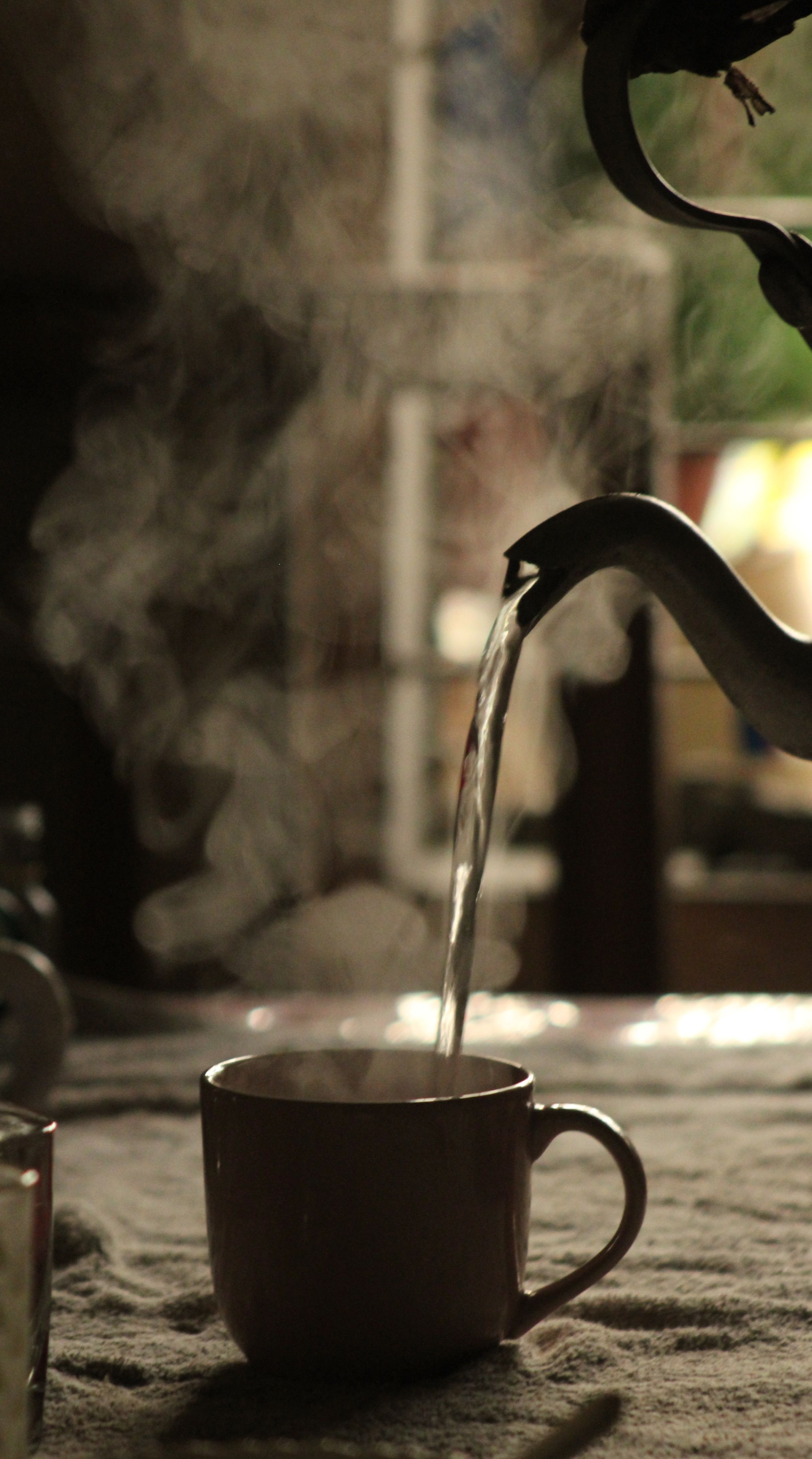 Fotomural Acogedora escena interior con vapor que se eleva mientras se vierte té caliente en una taza.