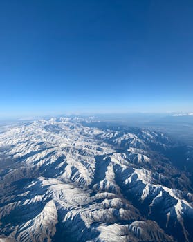 Aerial view of snow-covered mountain range in Nevada under a bright blue sky.