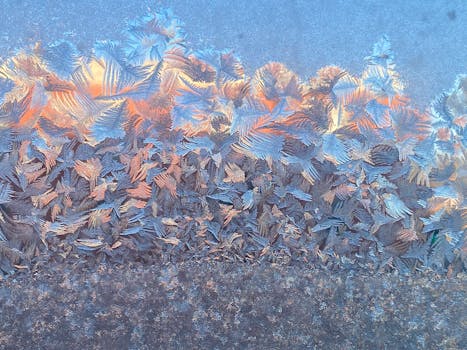Close-up view of beautiful frost patterns on a window, capturing the warm glow of sunrise.