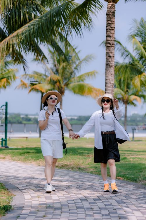 Free Two women enjoying a sunny walk in a lush tropical park holding hands. Stock Photo