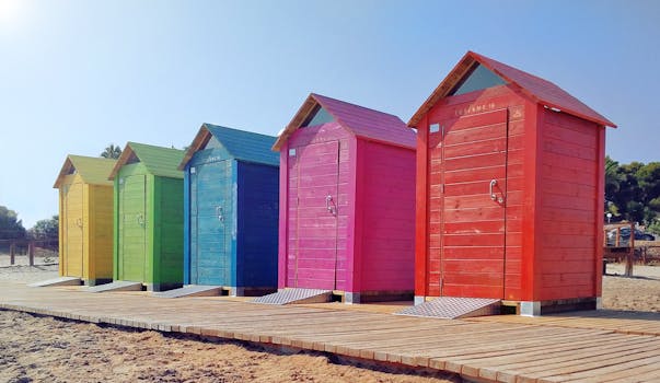 Colorful row of wooden beach huts on a sunny coastal day.