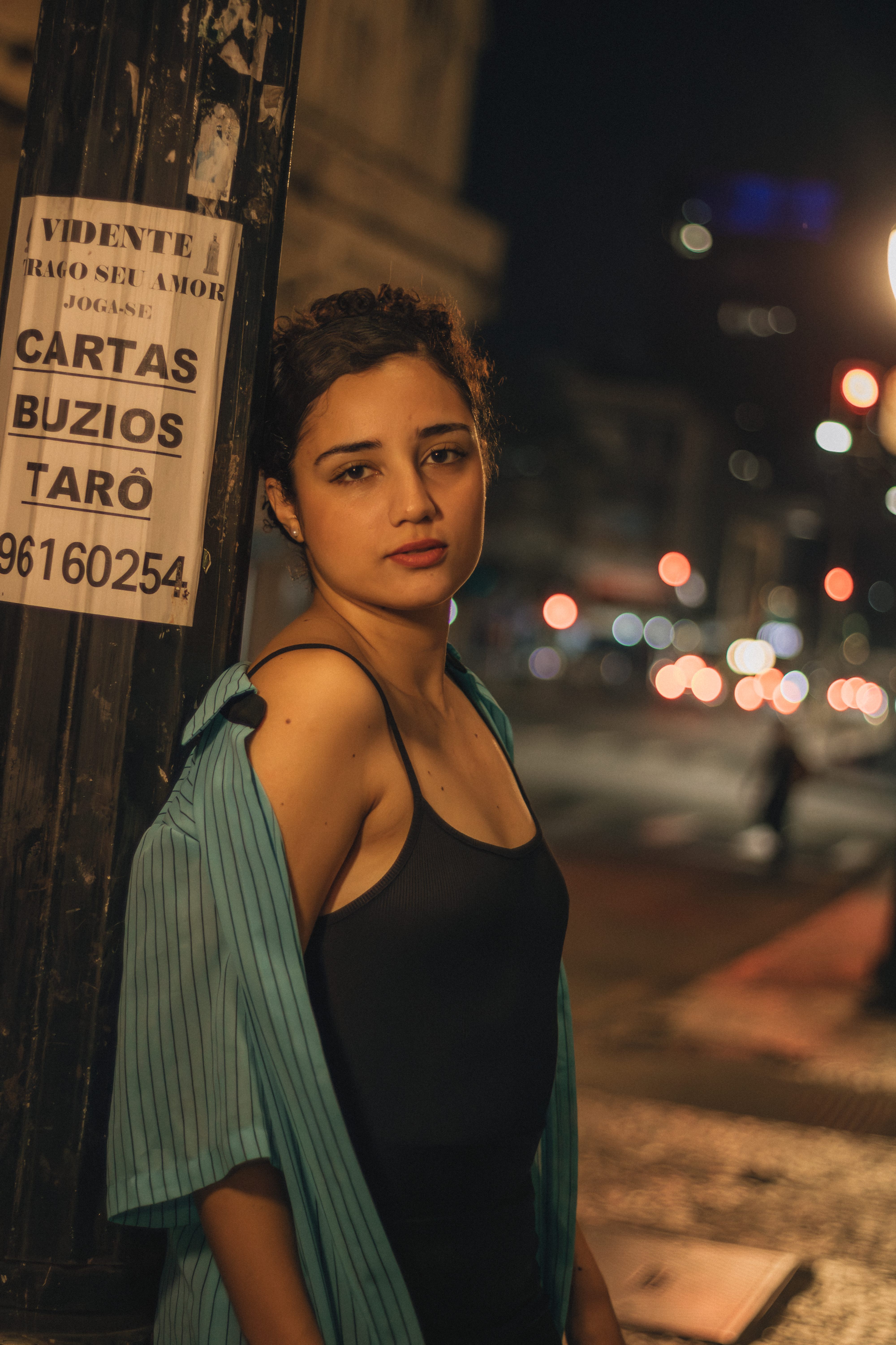 Young woman in city street at night, wearing casual outfit.