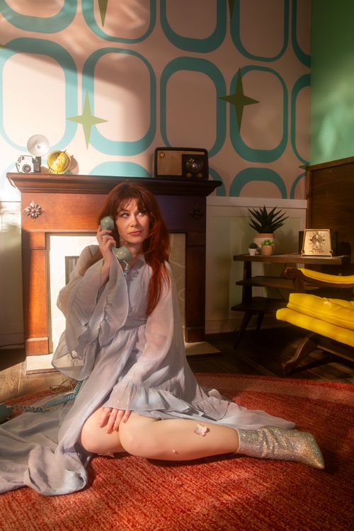 Free Elegant woman in retro-style living room with vintage phone, seated on a rug. Stock Photo