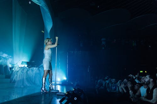 Free Woman in White T-shirt and White Shorts Standing on Stage Stock Photo