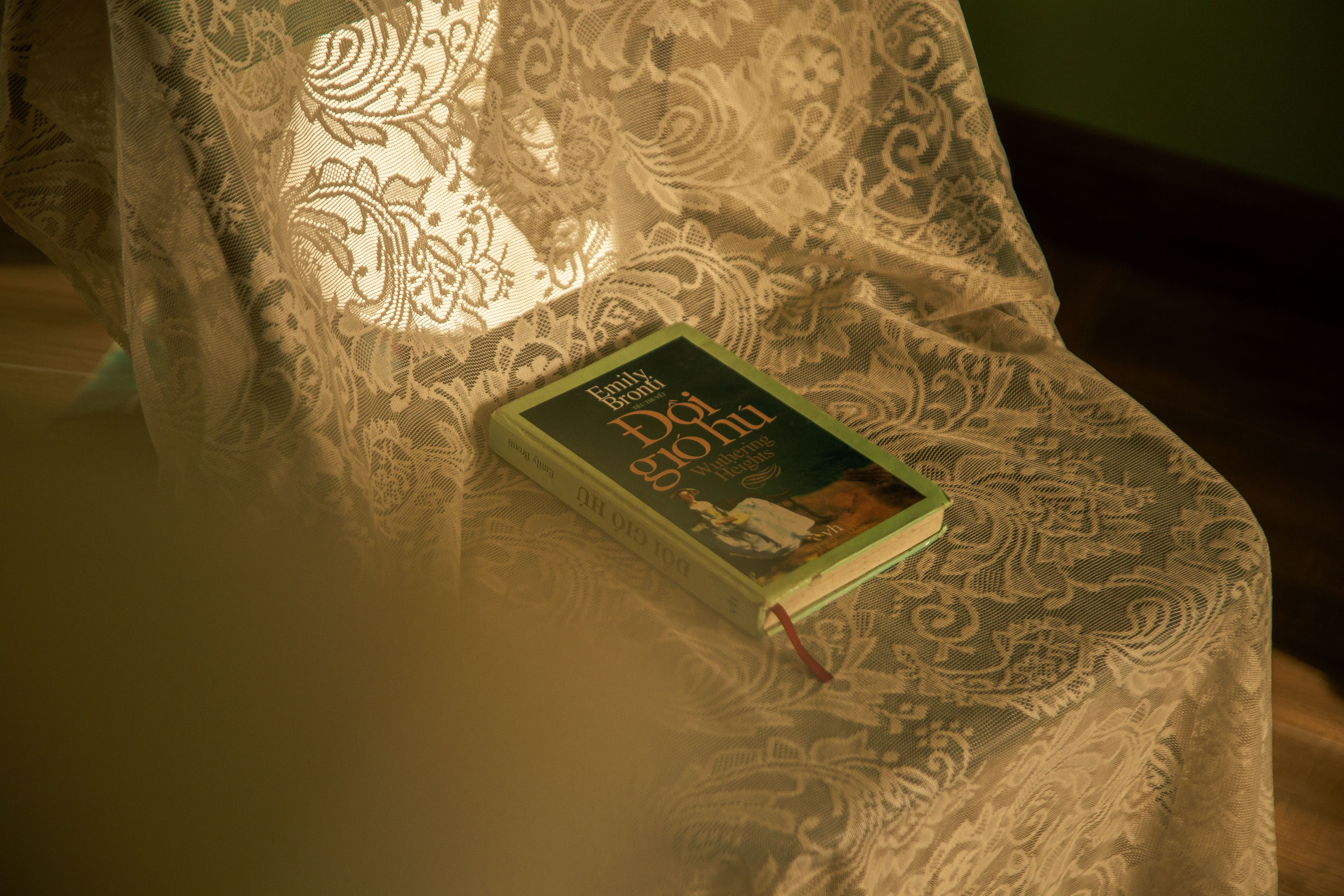 A book rests on a lace-draped chair, illuminated by warm ambient light.