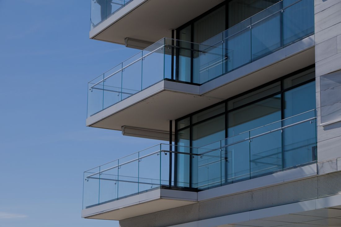 Sleek modern building with glass balconies against a clear blue sky