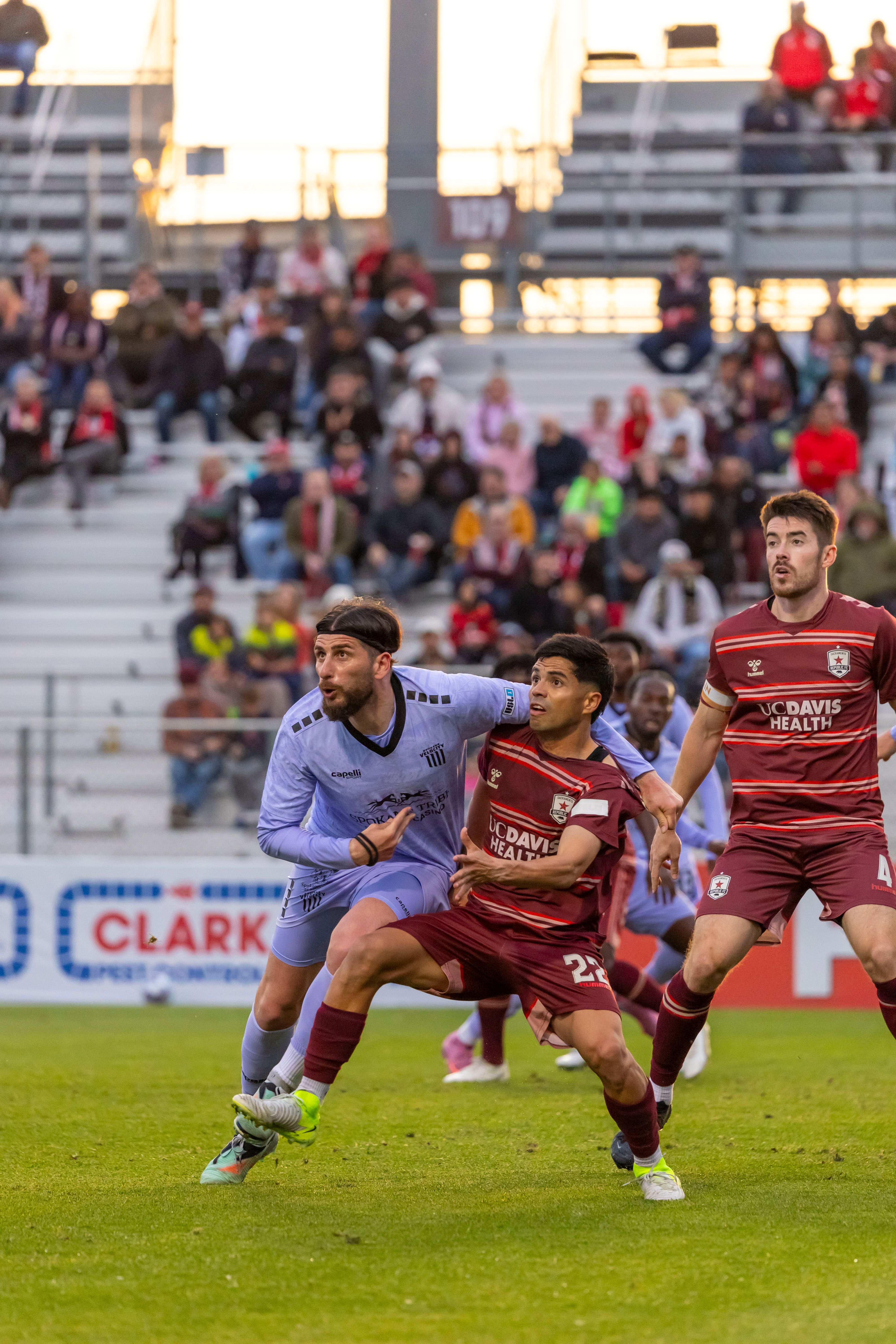 Soccer players in action during a competitive match in a stadium filled with enthusiastic fans.