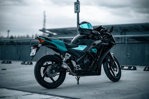 Free Black motorcycle with turquoise accents parked in an urban setting, showcasing modern design and sleek features. Stock Photo