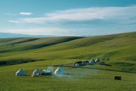 Picturesque view of small settlement with yurts in hilly area on sunny day on background of blue sky