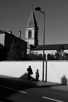 Silhouette of person walking by a church tower in black and white.