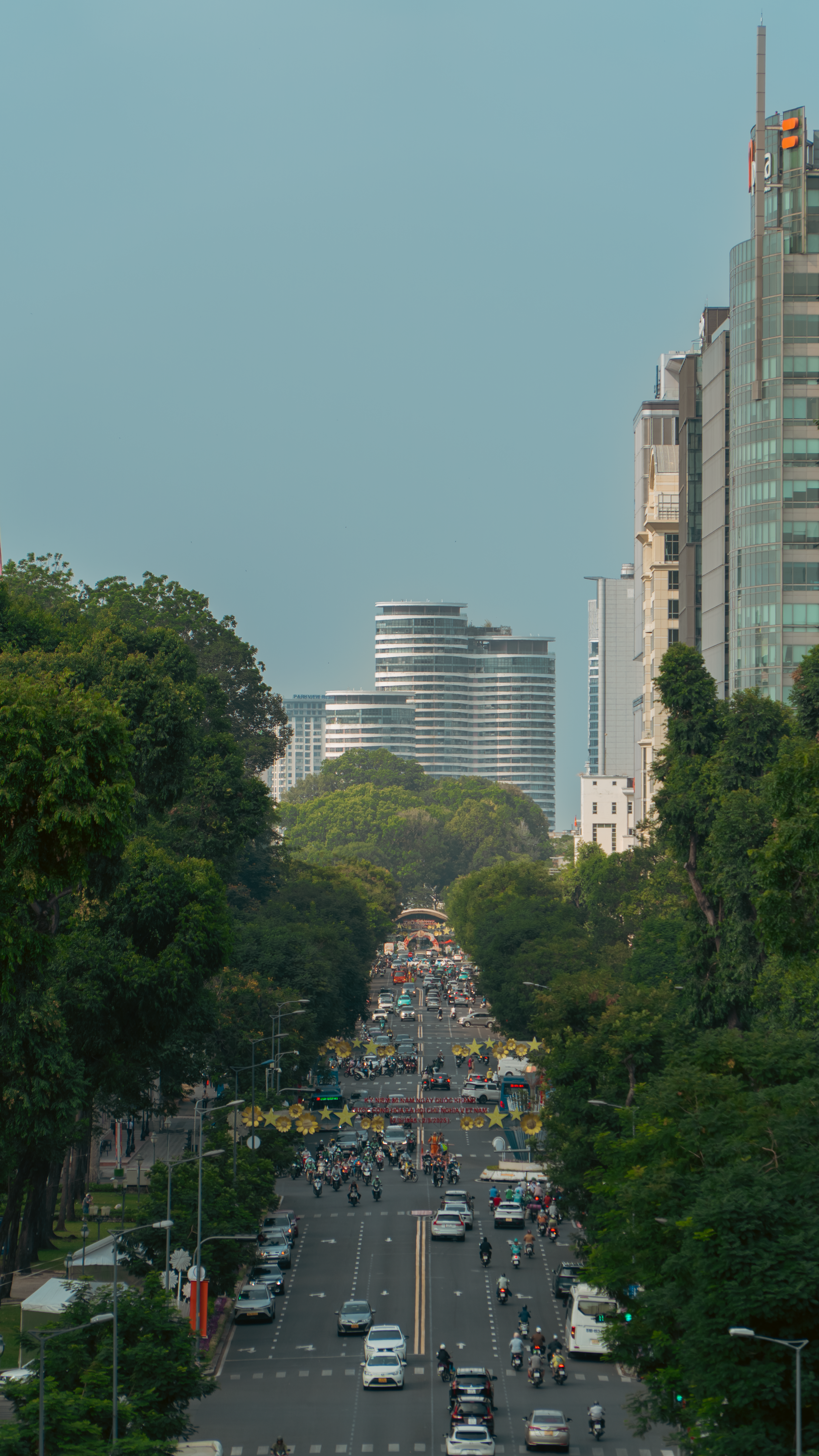 A vibrant city street flanked by skyscrapers and busy traffic under a clear sky.