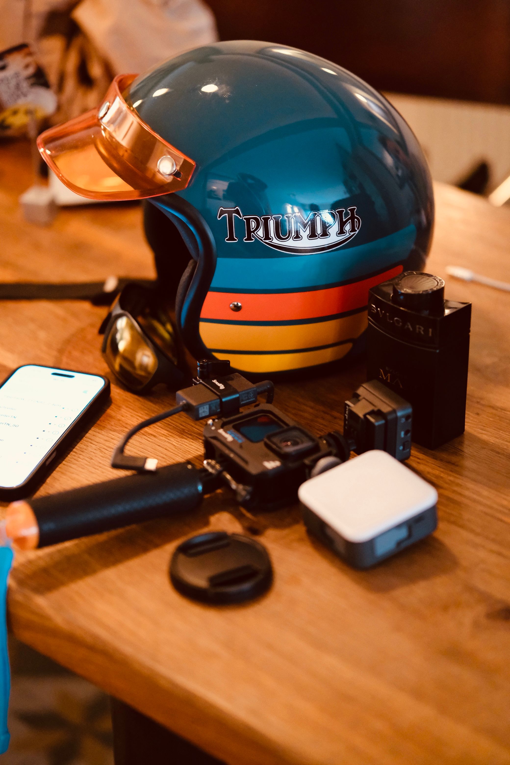 cadeau noël motard 100€ — sélection de cadeaux motard posés sur une table en bois brut : casque, gants, accessoires atelier