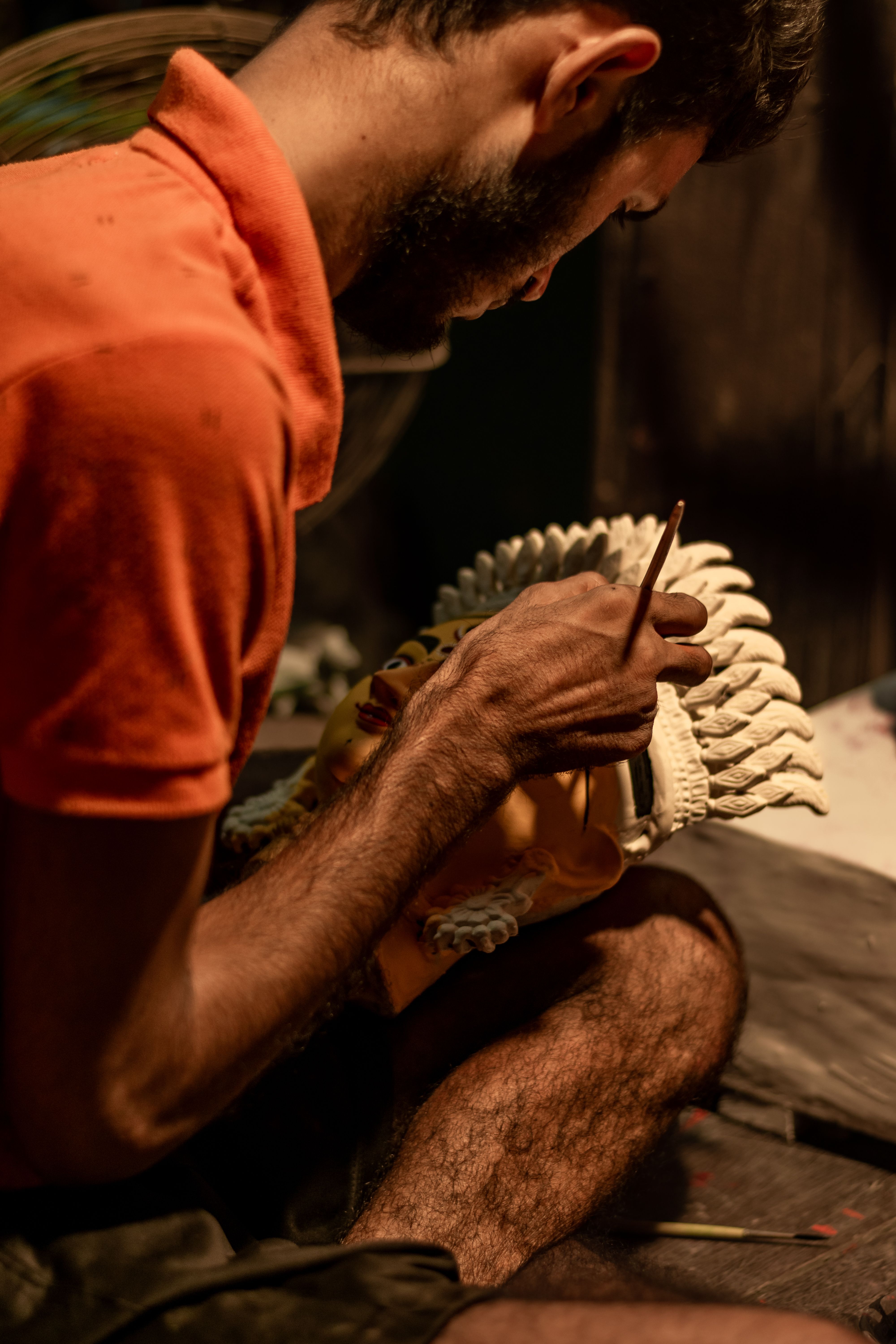 South Asian artisan skillfully crafting a clay idol, highlighting cultural artistry in Kolkata, India.