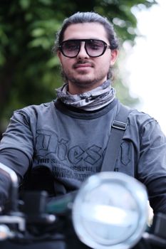 A young adult male biker wearing sunglasses and a casual shirt, enjoying a sunny day.