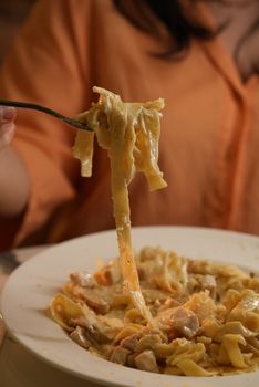 A creamy fettuccine alfredo pasta being enjoyed at a cozy restaurant setting.