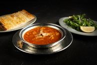 Delicious Turkish lamb soup with pita bread and fresh arugula salad on a dark background.