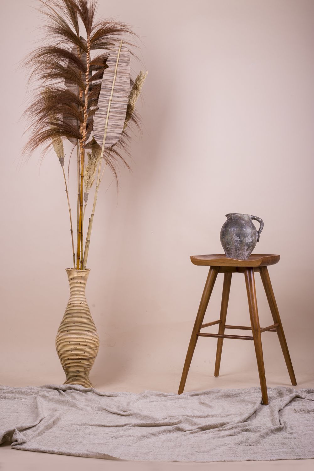 Dried plants in a ceramic vase and jug on a wooden stool