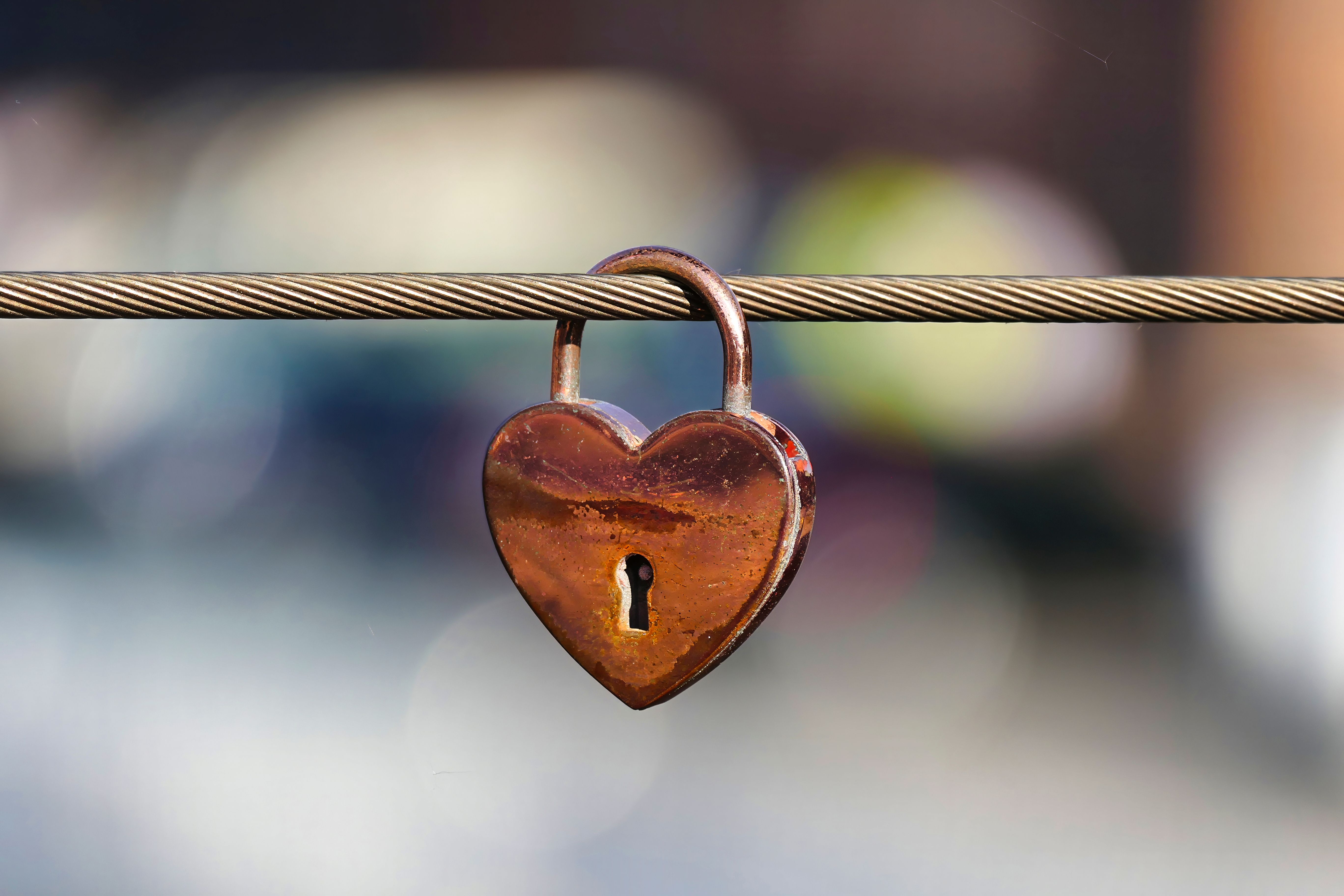 A close-up of a heart-shaped lock symbolizing love on a metal cable.