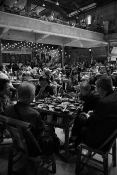 A lively restaurant filled with people enjoying meals in a vibrant social setting, captured in black and white.