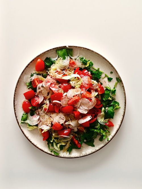 Free Colorful salad with cherry tomatoes, onions, and fresh greens in a white bowl. Stock Photo