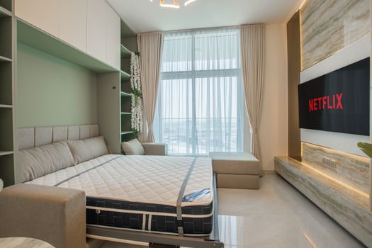 Spacious and elegant bedroom featuring a cozy bed, large window, and Netflix on TV.