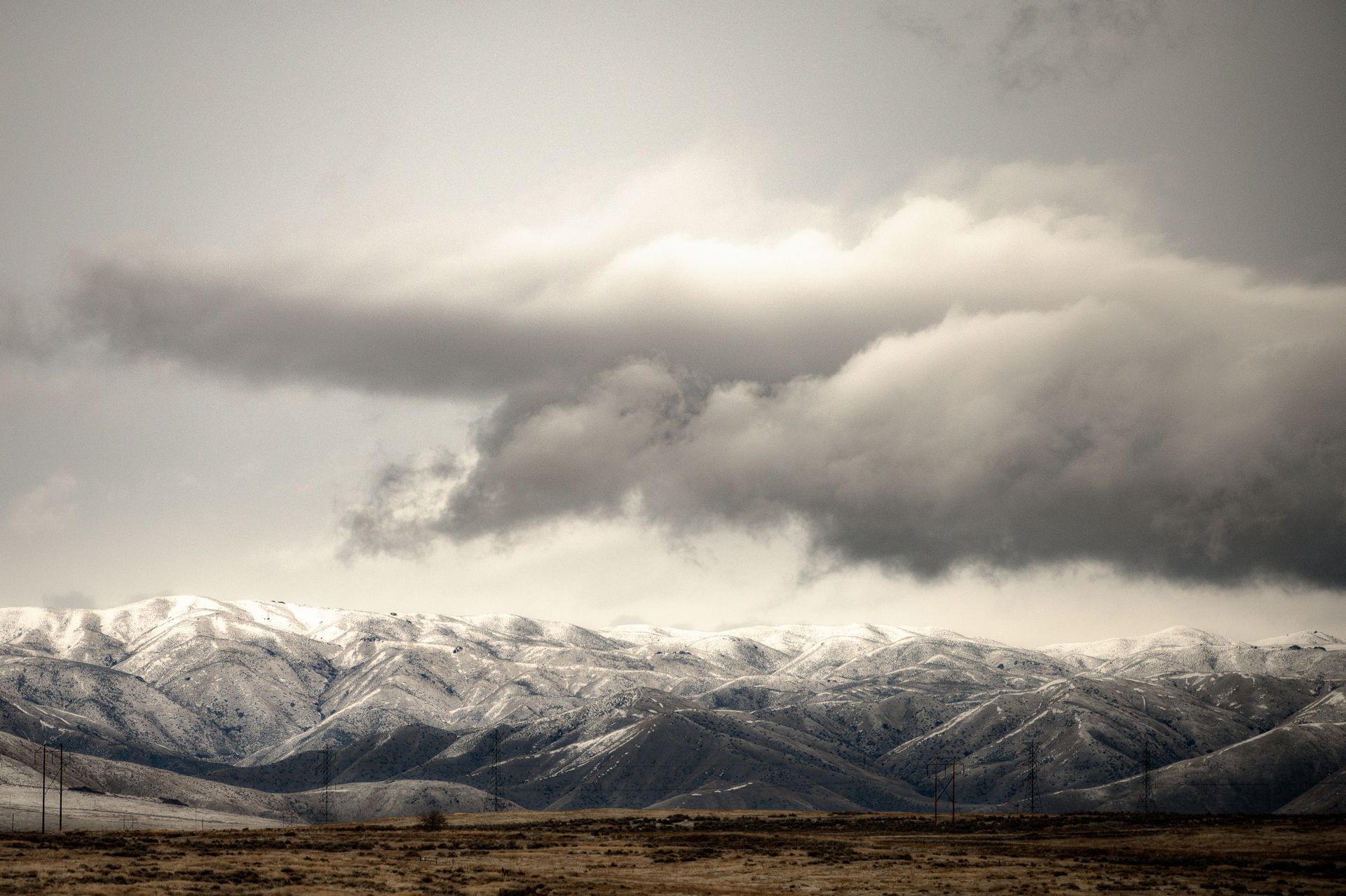 Breathtaking landscape of rough mountain range covered with snow on background of thunderstorm sky in winter