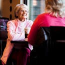 两位女士在舒适的咖啡馆里喝着咖啡，热烈地交谈着