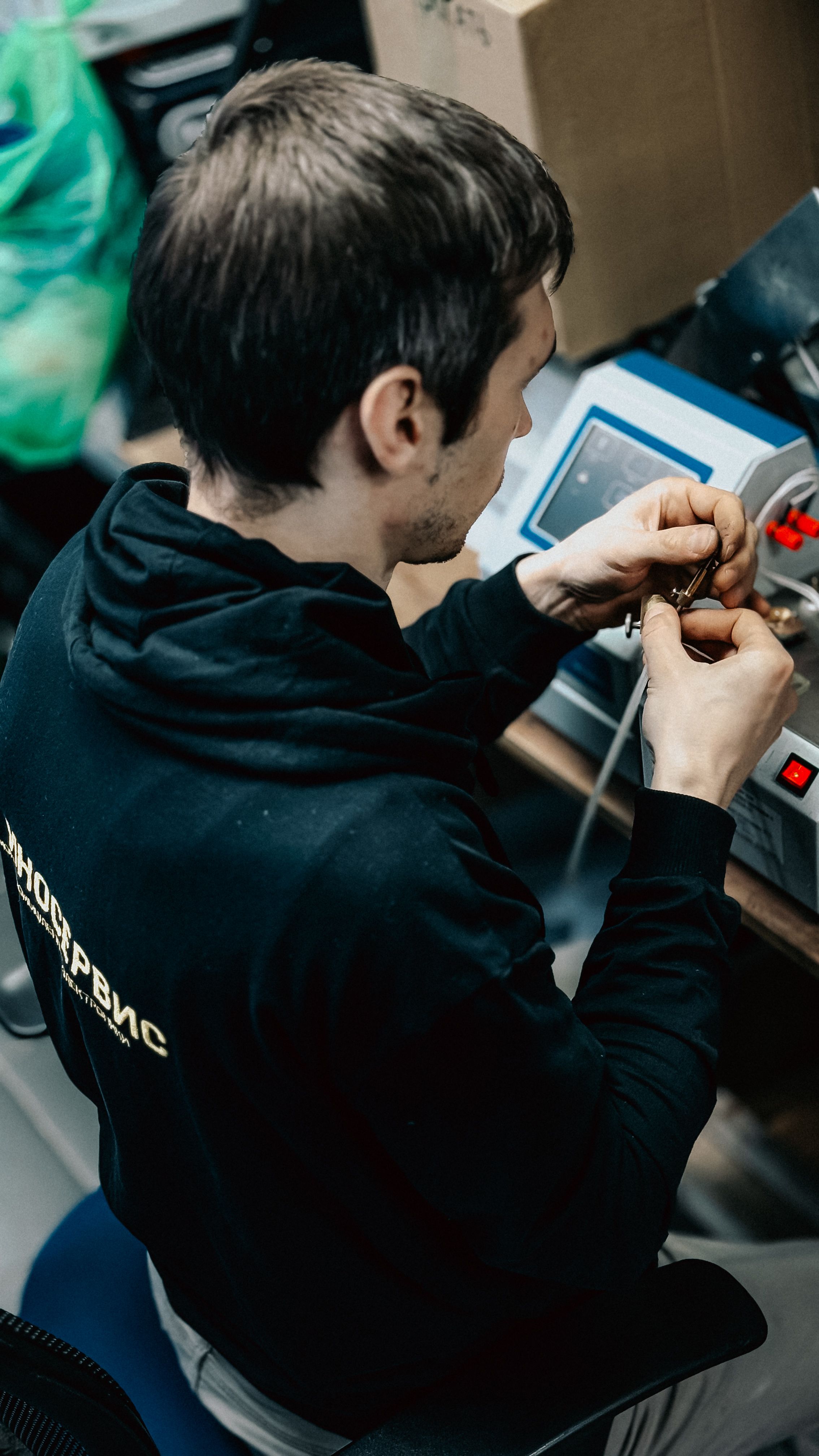 A technician focused on repairing an electronic device in a workshop environment, showcasing technical skills and precision.