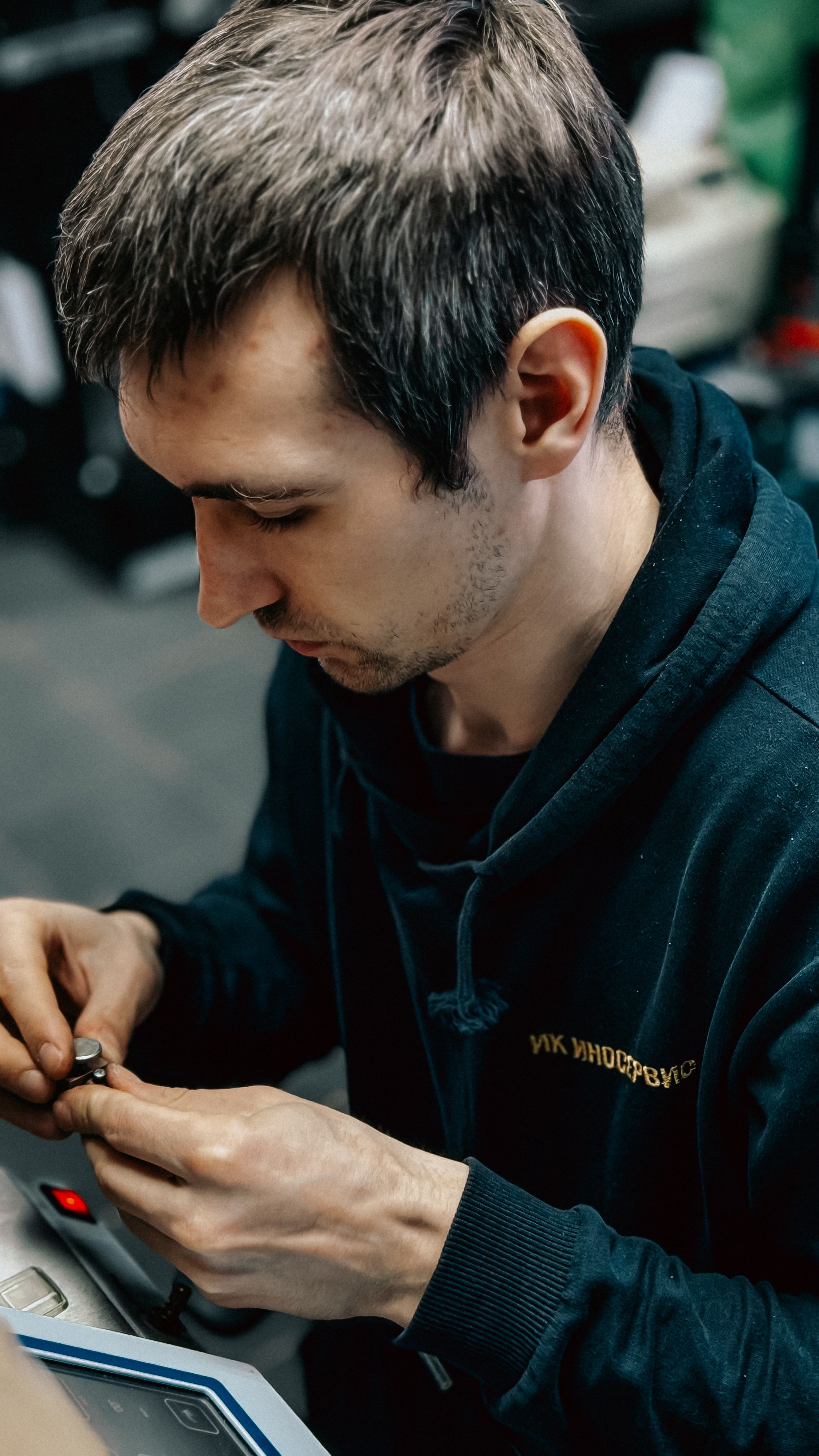 A concentrated adult working on intricate electronics indoors, showcasing precise skills.