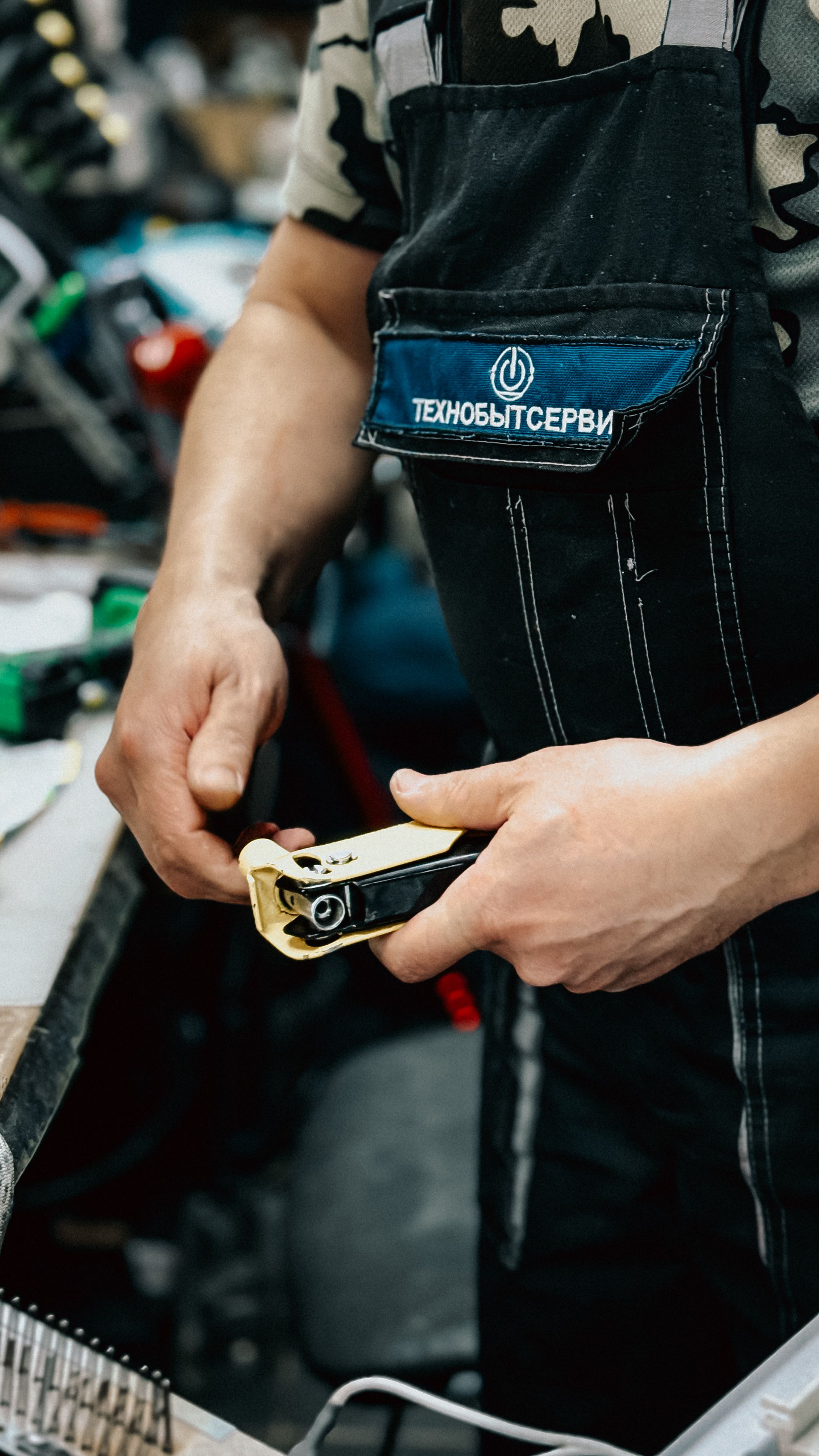 A worker in overalls using a plumbing tool in an indoor workshop setting, showcasing hands-on craftsmanship.