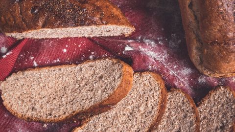 A rustic arrangement of freshly baked bread with slices on a red cloth, showcasing a warm, artisanal look.