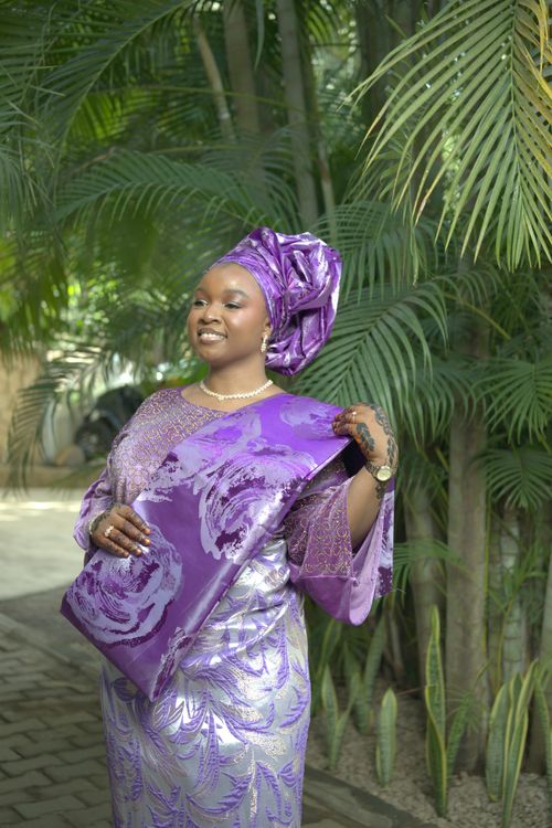 Free Smiling woman in vibrant traditional attire with lush green background. Stock Photo