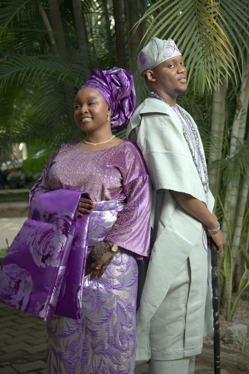 Free Couple in vibrant traditional Nigerian attire posing back-to-back outdoors. Stock Photo