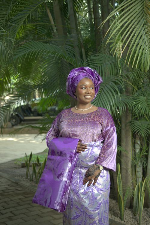 Free A woman in vibrant traditional Nigerian attire poses outdoors amidst lush greenery. Stock Photo