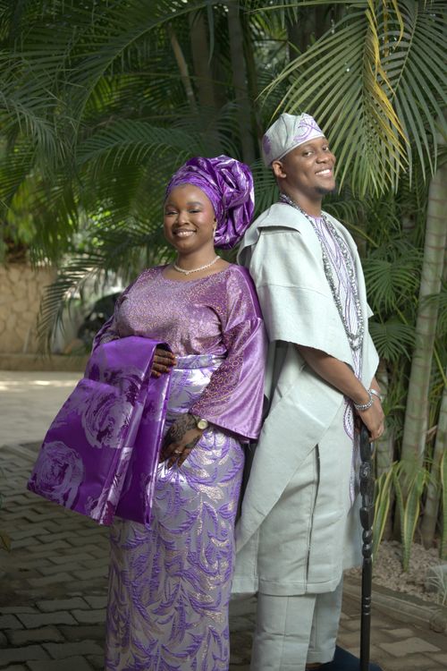 Free Nigerian couple dressed in vibrant traditional attire, smiling outdoors. Stock Photo