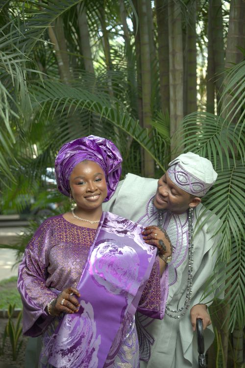 Free Happy Nigerian couple in traditional attire enjoying a moment outdoors surrounded by lush greenery. Stock Photo