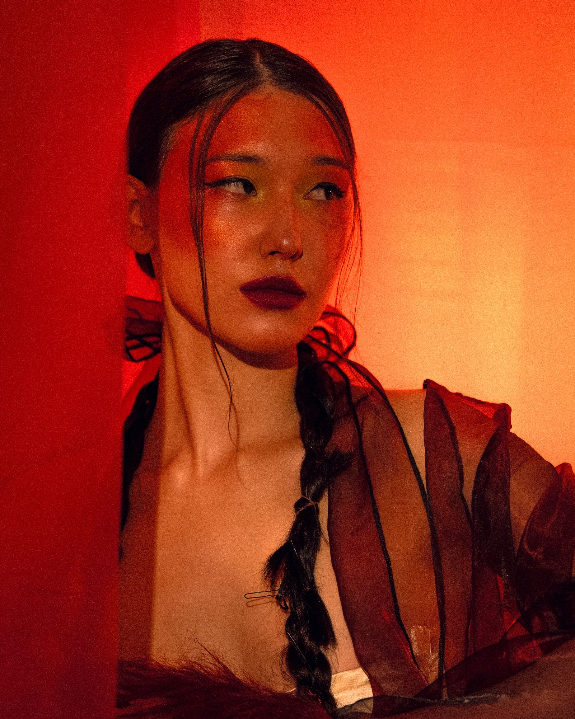 Vibrant portrait of a woman with dramatic red lighting and artistic makeup.