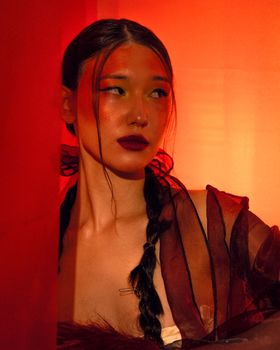 Vibrant portrait of a woman with dramatic red lighting and artistic makeup.