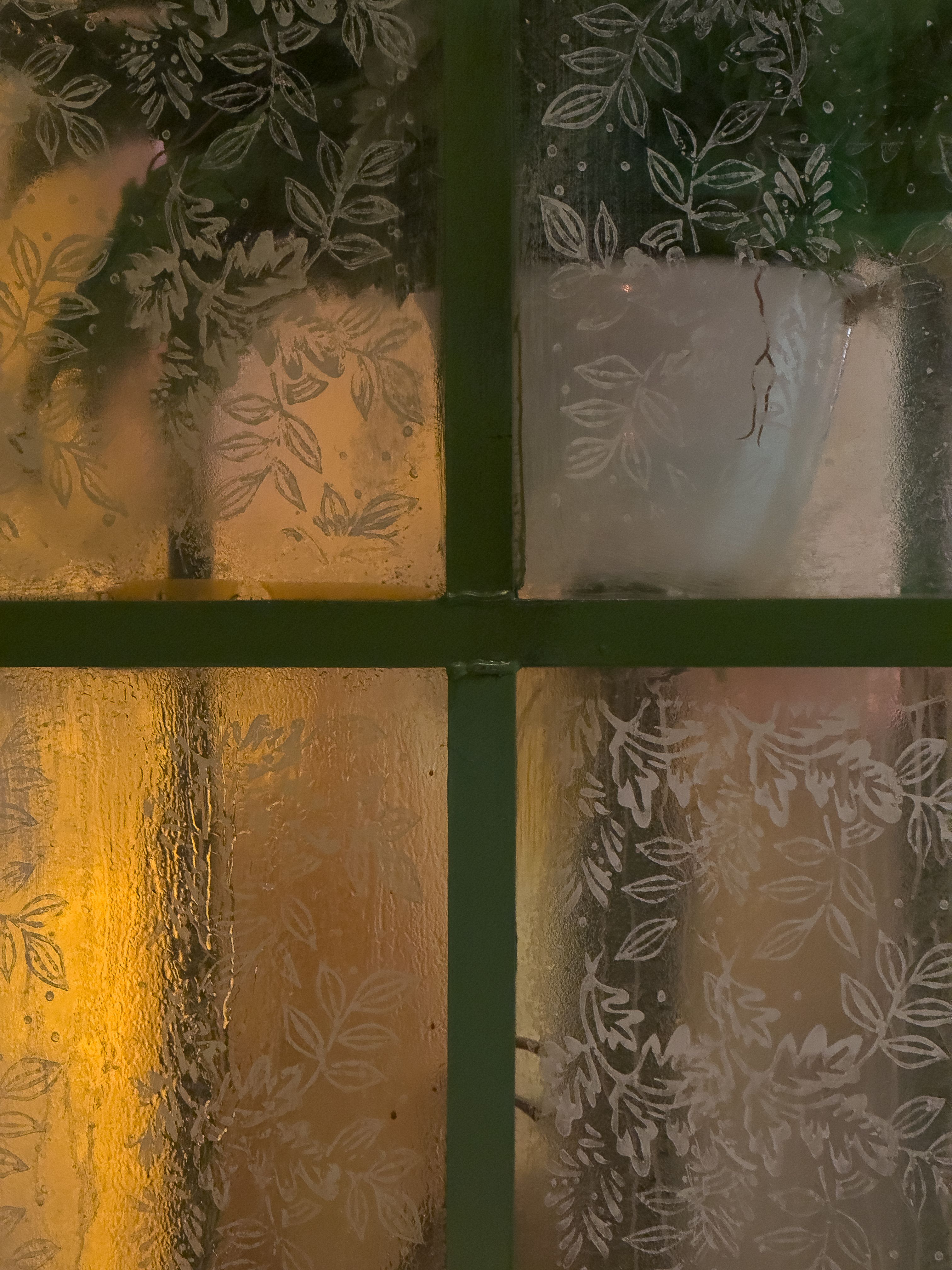 Free Frosted glass window with leaf patterns and warm light glowing through. Stock Photo