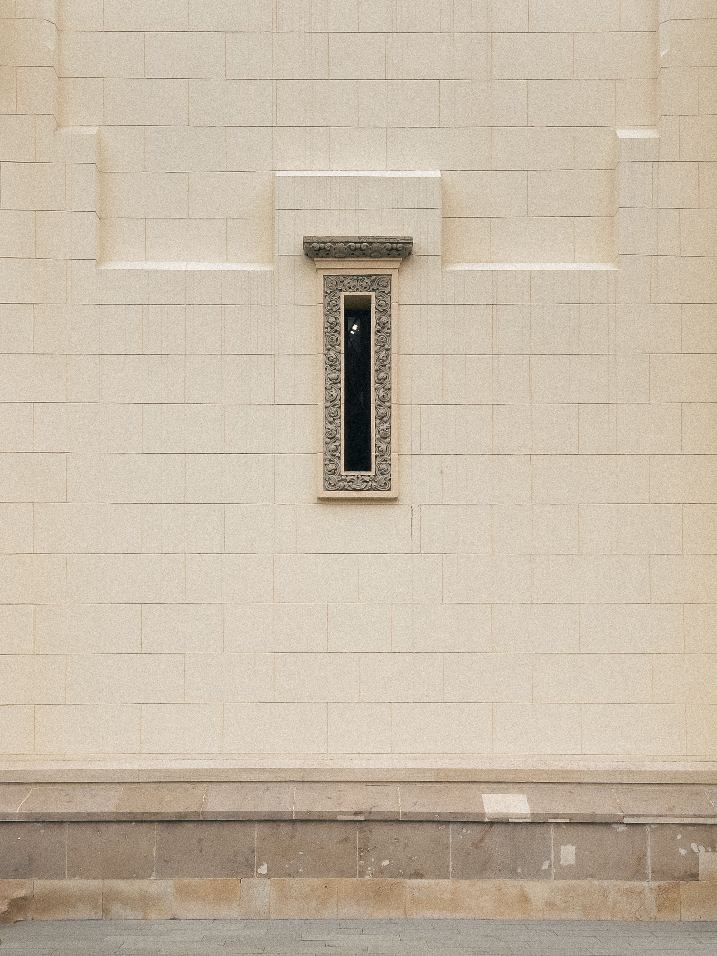 Free Minimalist wall with ornate window, showcasing architectural elegance and simplicity. Stock Photo