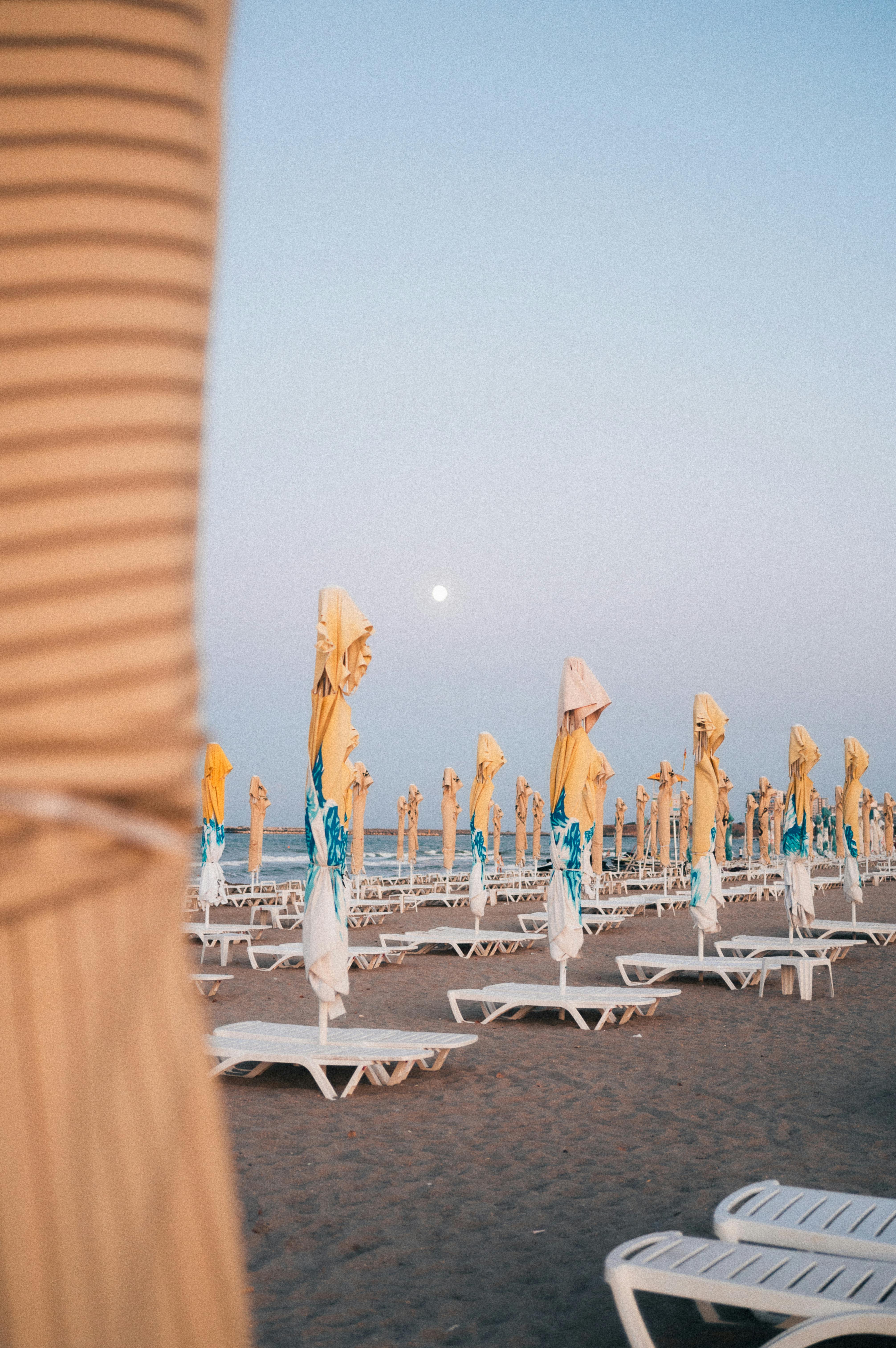 A serene beach scene with closed umbrellas at twilight, creating a peaceful atmosphere.