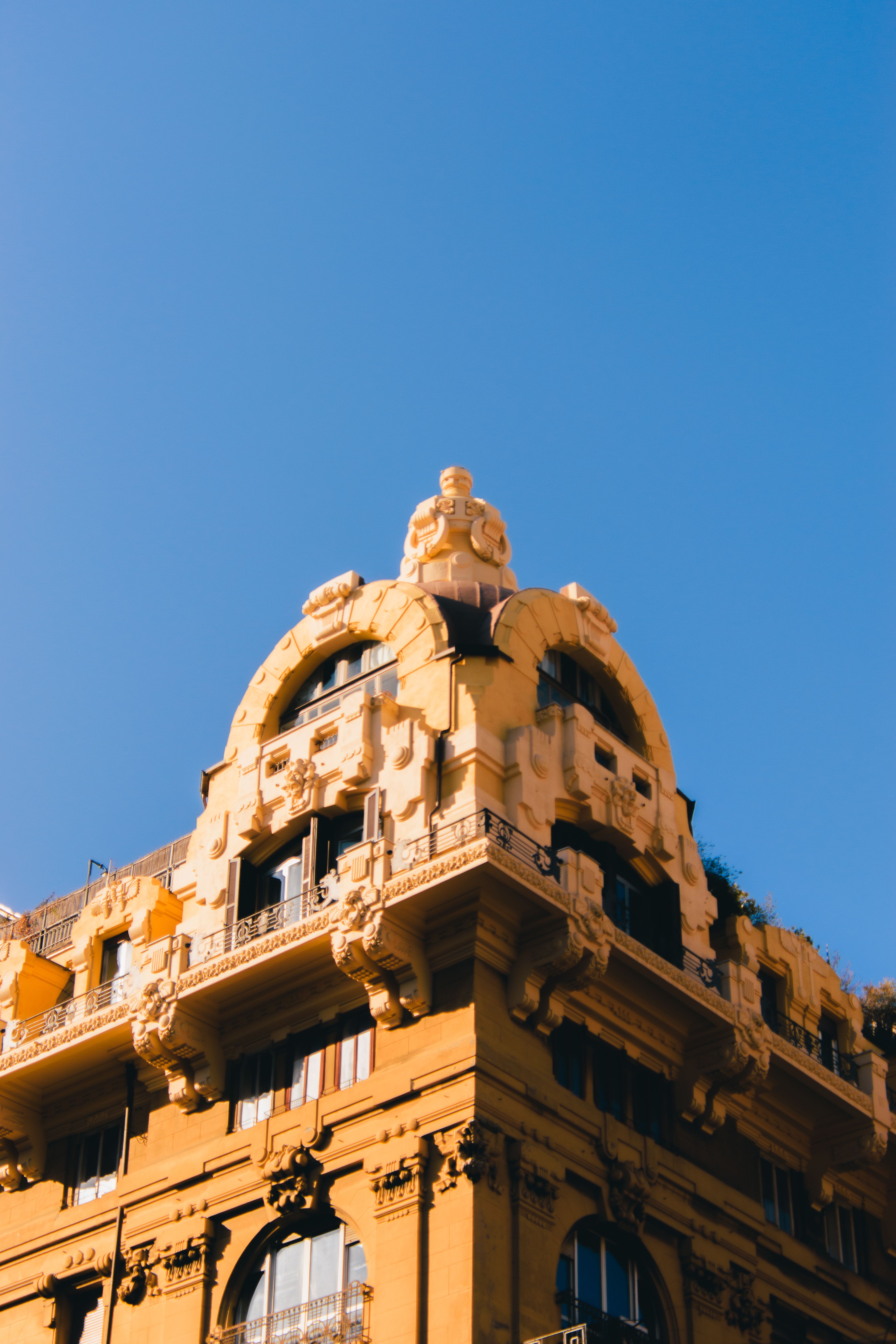 Free Elegant architectural details of a historic building facade under a clear blue sky. Stock Photo