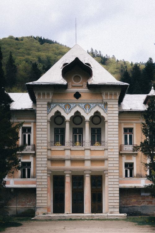 Free Elegant historic building set against a lush green mountainous background. Stock Photo