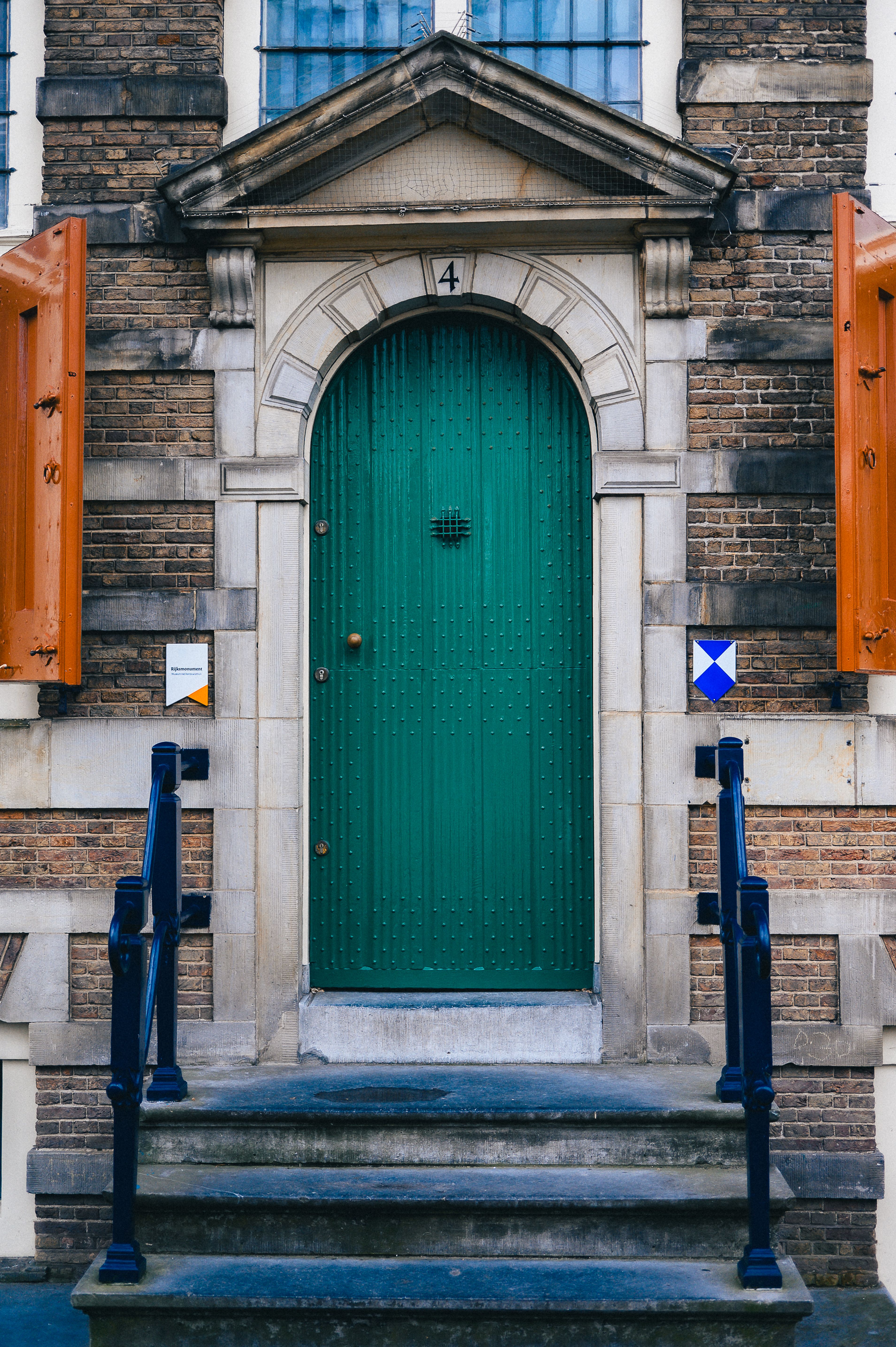 Historic European facade featuring a distinctive green door and stone archway.