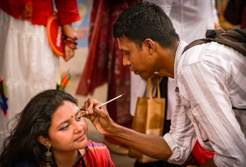Free Artist skillfully paints bindi on woman's forehead at vibrant cultural festival. Stock Photo